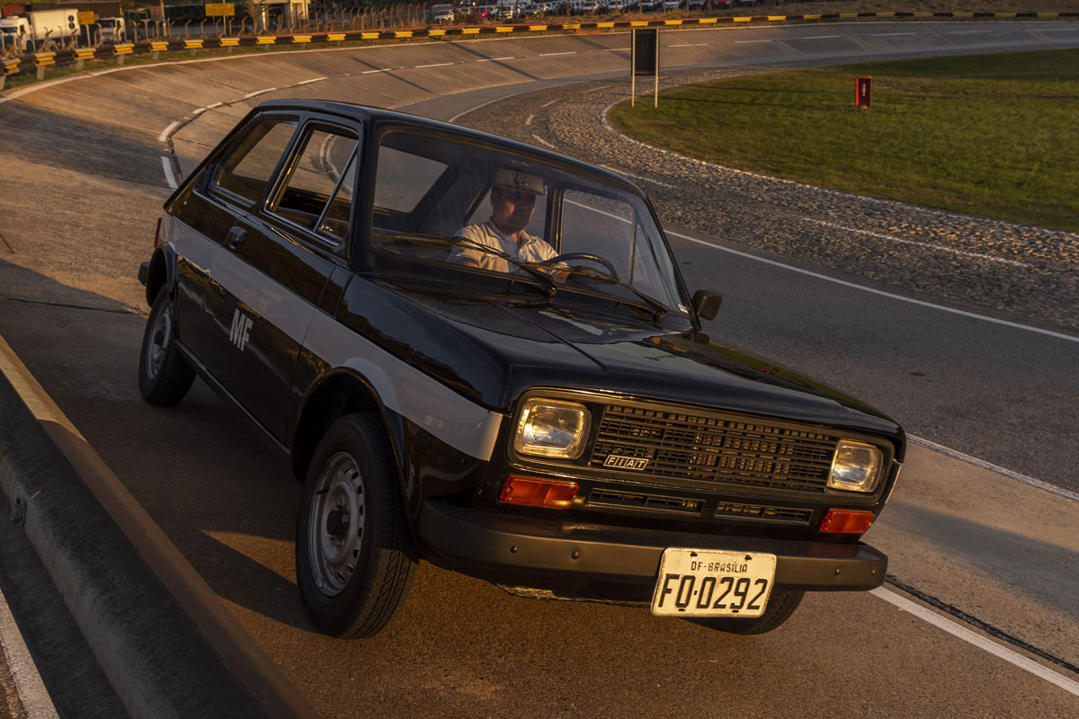 Fiat 147 azul com faixa lateral branca andando na pista