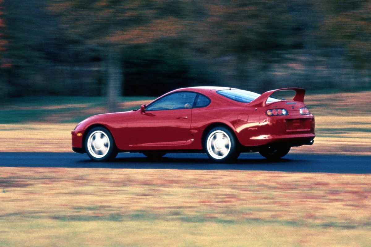 Toyota Supra vermelho andando na pista e exibindo o aerofólio traseiro curvado