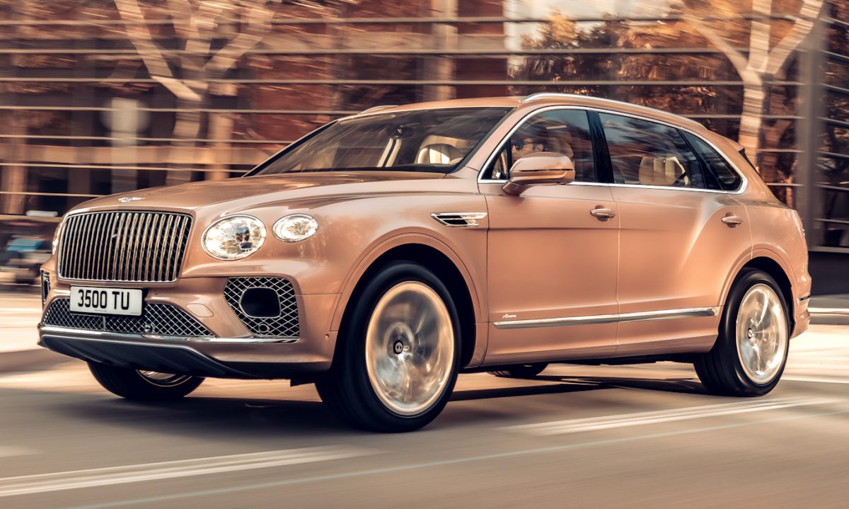 Bentley Bentayga bronze em movimento na cidade com prédio e árvores ao fundo [Divulgação]