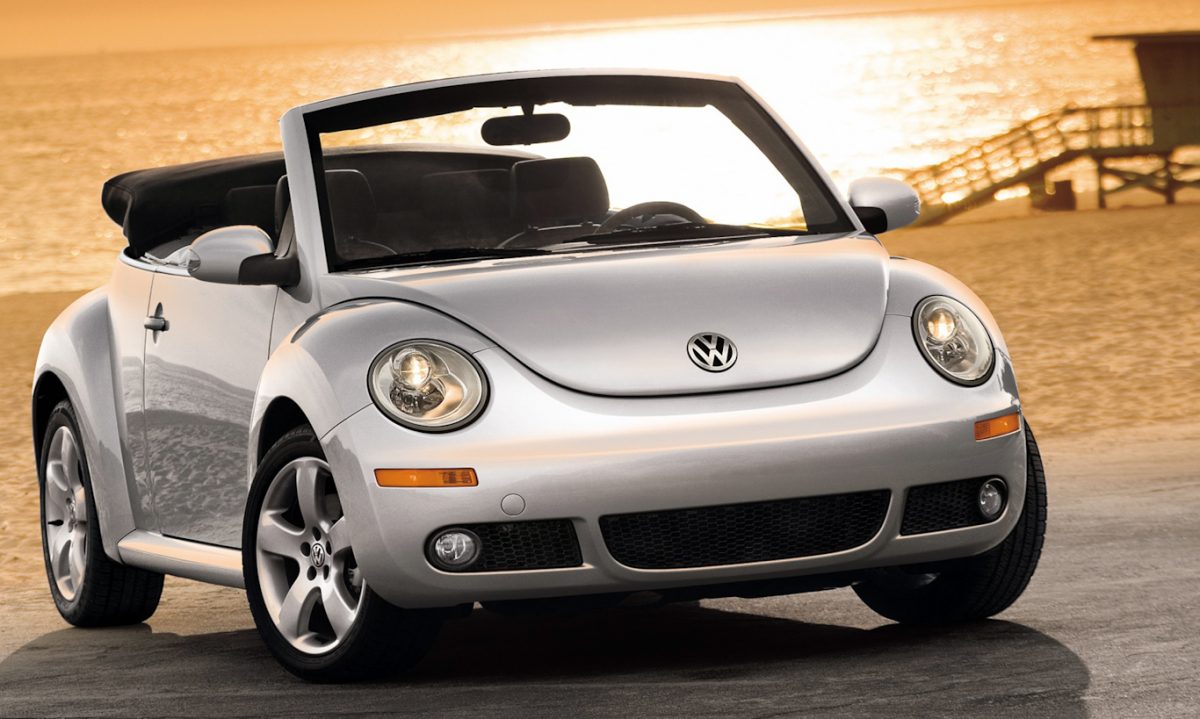 Volkswagen New Beetle conversível prata em foto de dianteira com praia ao fundo [Divulgação]