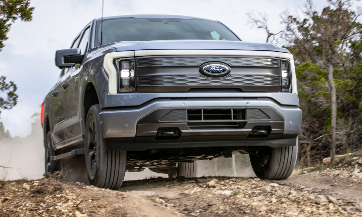 Ford F-150 Lightning cinza em foto de dianteira com árvores ao fundo