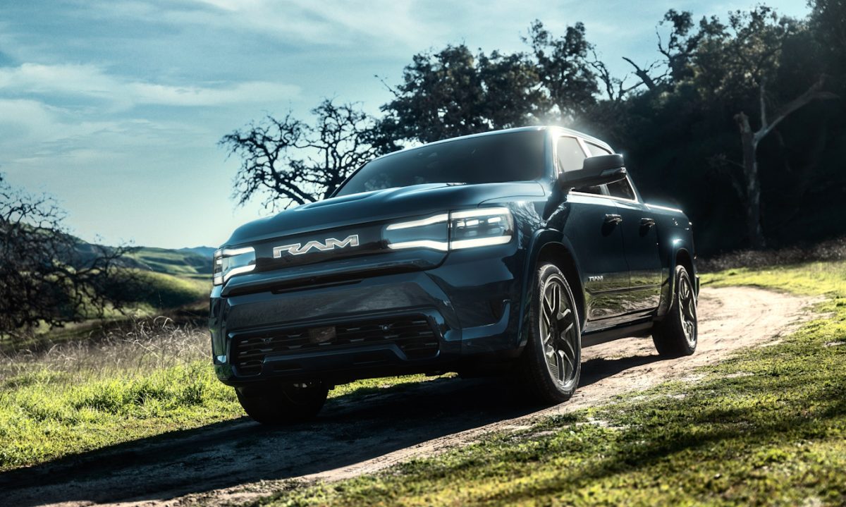 RAM 1500 REV 2025 andando na terra com árvores ao fundo e céu azul