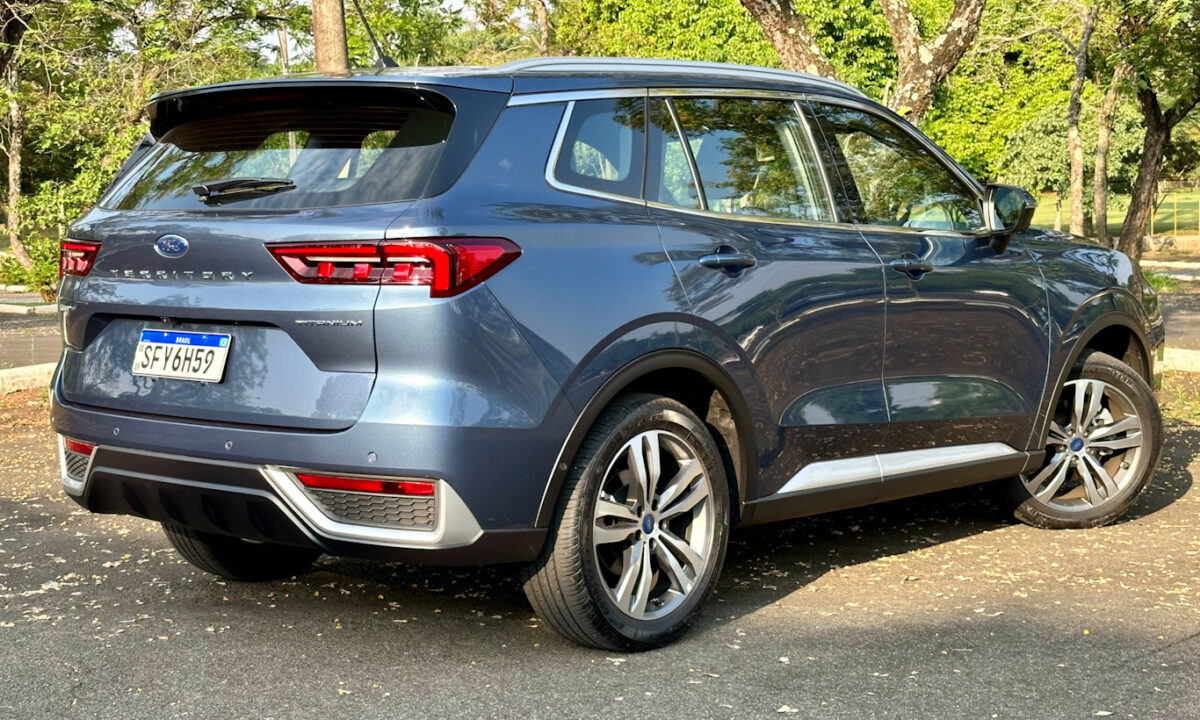 Ford Territory Titanium azul de traseira no sol com uma floresta ao fundo
