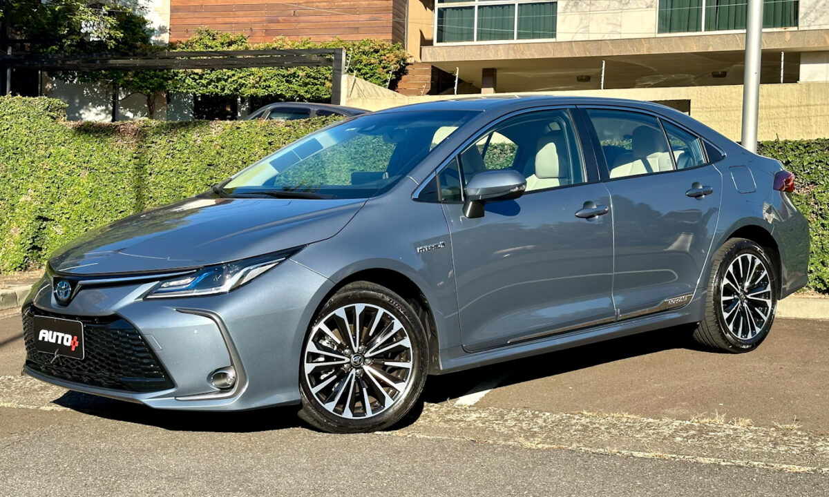 Toyota Corolla Altis Premium Hybrid azul parado de frente com planta e casa ao fundo