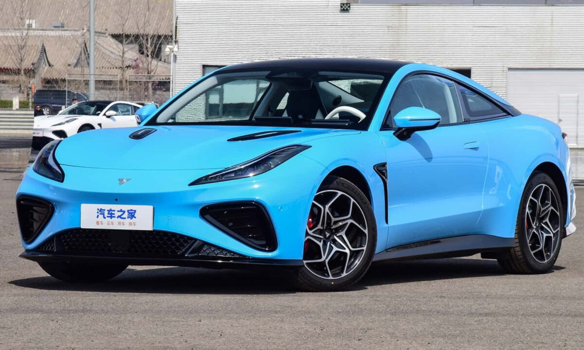 Neta GT azul parado de frente com as rodas dianteiras viradas e muro ao fundo