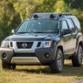 Nissan Xterra cinza parado na grama com árvores ao fundo