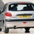 Peugeot 206 prata de traseira com uma placa amarela da Europa