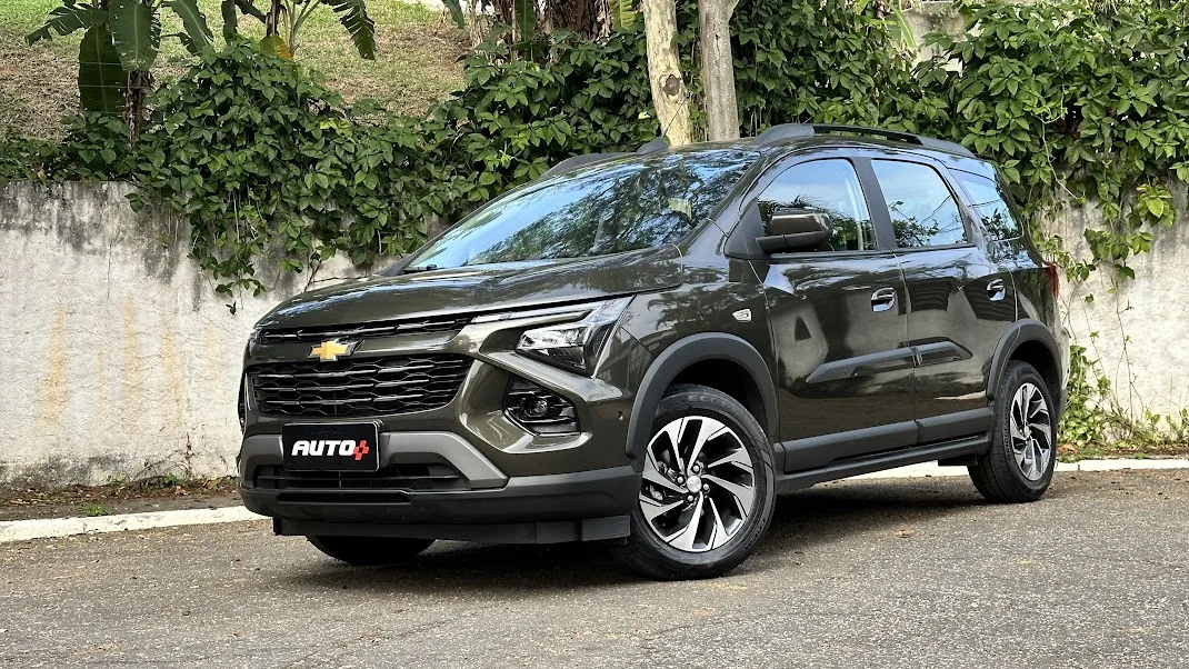 Chevrolet Spin Premier verde de frente com um muro branco sujo ao fundo
