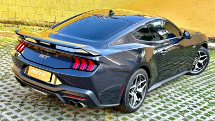 Ford Mustang Coupé cinza com muro amarelo ao fundo é um dos carros que não oferecem uma grande visibilidade do banco traseiro