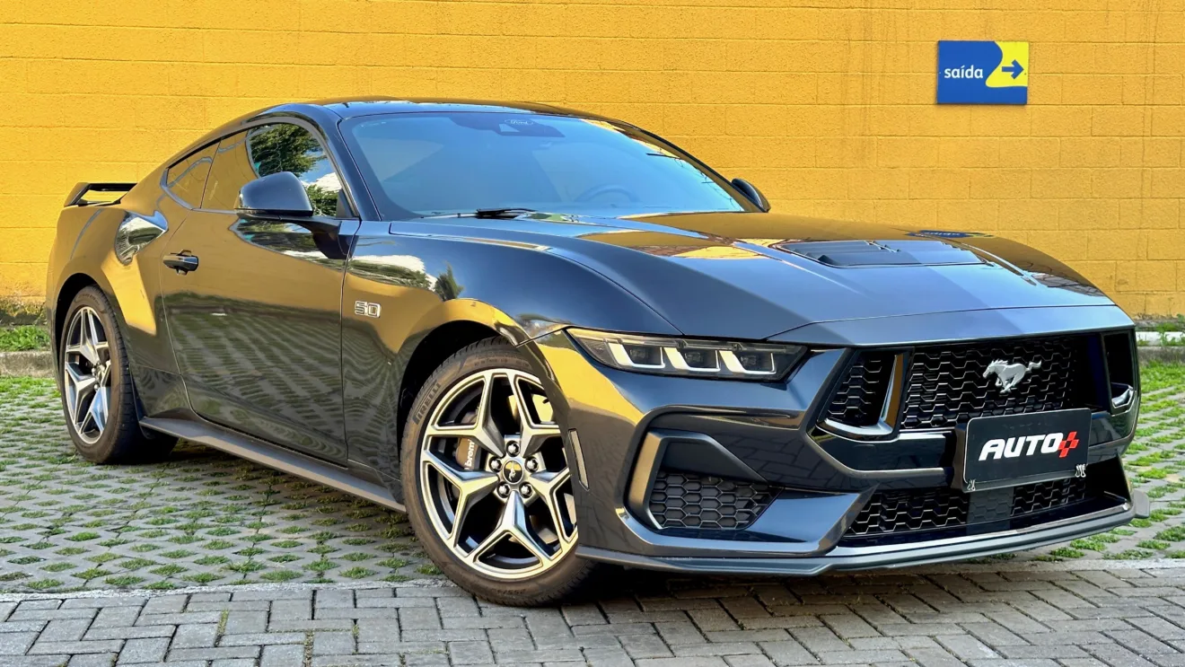 Ford Mustang GT cinza de frente em um muro amarelo