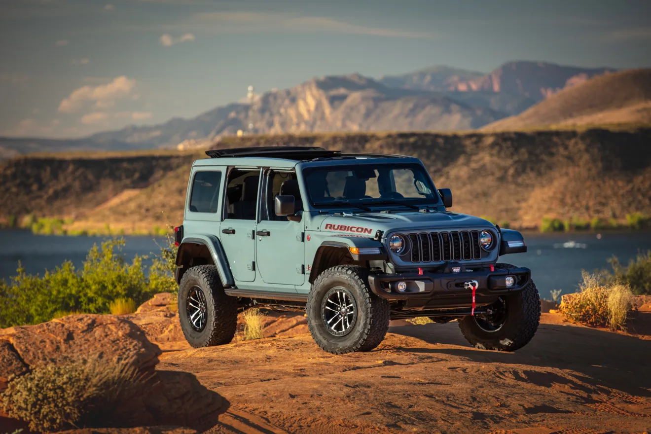 Jeep Wrangler é um dos carros símbolos dos Estados Unidos e o modelo 2025 azul está parado em cima de uma montanha com lago ao fundo