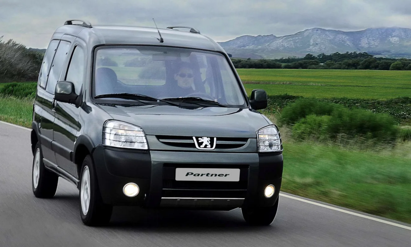 Peugeot Partner Patagonica andando no asfalto com grama e árvores ao fundo