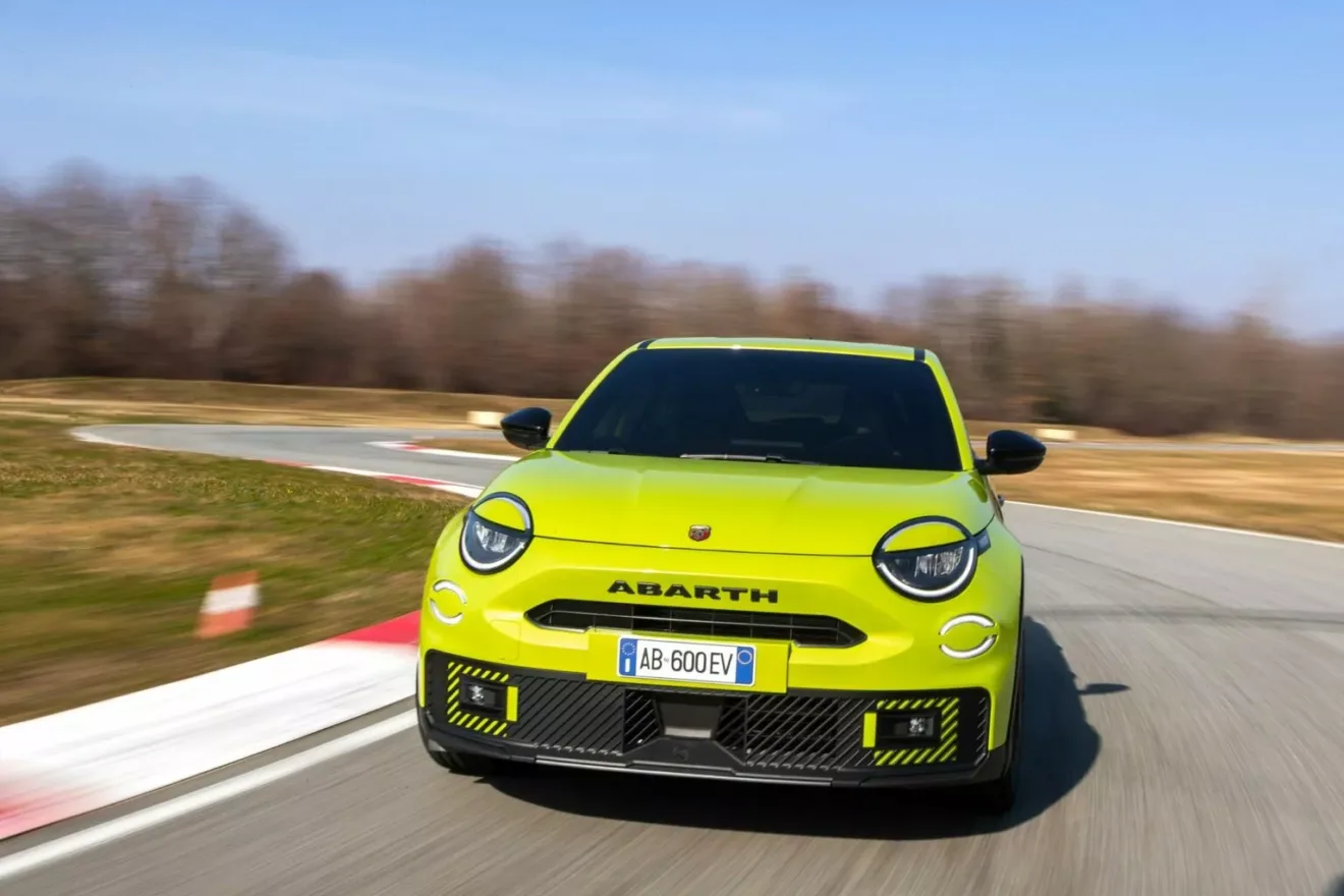 Foto do interior do Abarth 600e com o volante de dois raios e detalhes em amarelo nos bancos e no volante