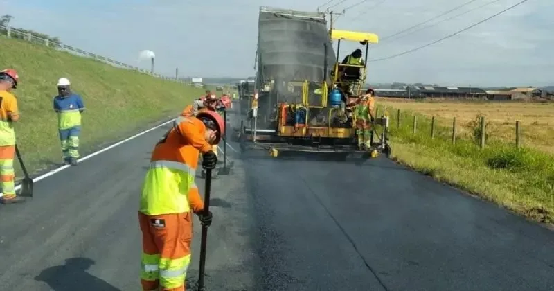 Trabalhadores de laranja fazendo obras na BR-101 com maquinário ligado