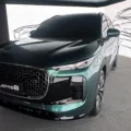 Chery Lepas 8 verde de frente em um fundo com desenhos do SUV que parece um Porsche Cayenne