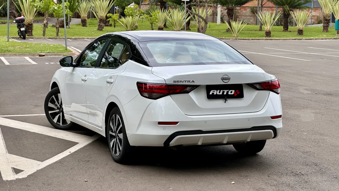 Nissan sentra exclusive branco com teto preto parado em frente árvores bem grandes