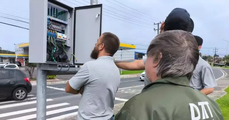 Central semafórica sendo testada e técnicos avaliando o funcionamento com avenida ao fundo