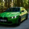 Novo BMW M3 Competition Track verde em foto 3x4 frontal na estrada