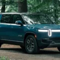 Rivian R1S azul parado em meio a floresta