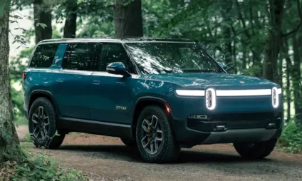 Rivian R1S azul parado em meio a floresta