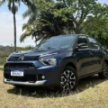 Citroën Basalt Shine Turbo 200 azul parado em meio a um gramado com uma floresta ao fundo