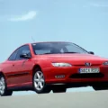 O design Pininfarina Peugeot 406 Coupé vermelho em foto de frente com o céu azul