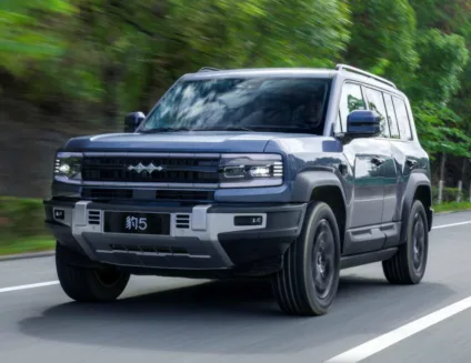 Fang Cheng Bao 5 azul em foto de movimento na estrada de asfalto com plantas ao fundo