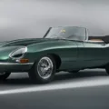 Jaguar E-Type verde em foto estática de dianteira com o chão e o fundo em cinza