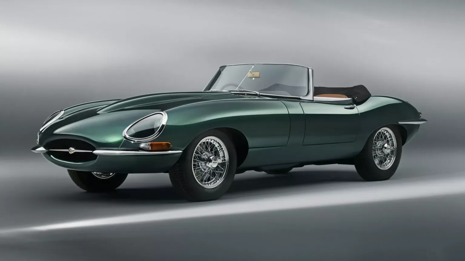 Jaguar E-Type verde em foto estática de dianteira com o chão e o fundo em cinza