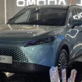 Omoda 7 híbrido plug-in azul estacionado em um estande com pedras coloridas ao seu redor