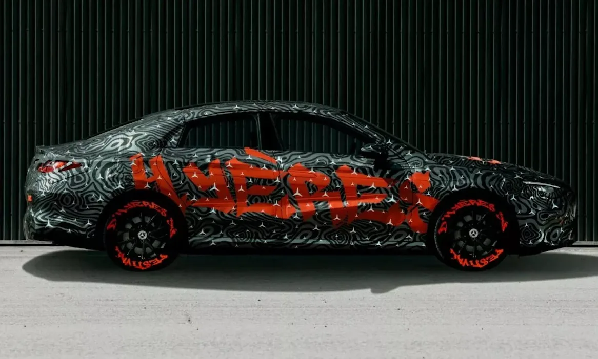 Novo Mercedes-Benz CLA camuflado de cinza, preto e laranja visto de lado com fundo escurecido