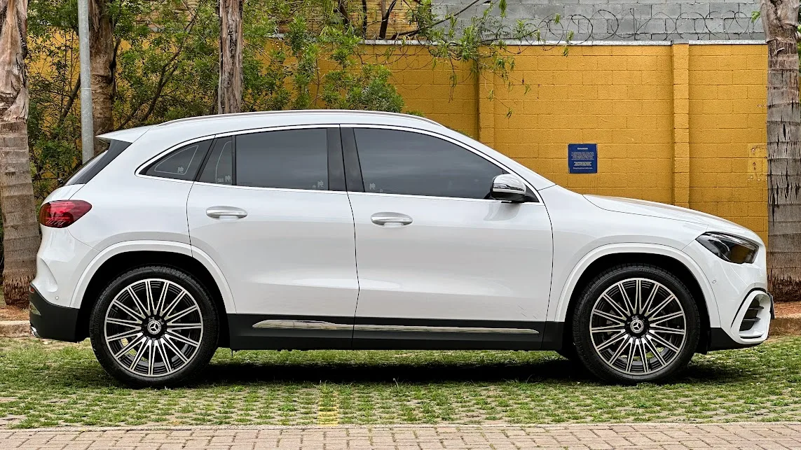 Mercedes-Benz GLA 200 AMG Line branco em foto de lateral com muro amarelo e plantas ao fundo