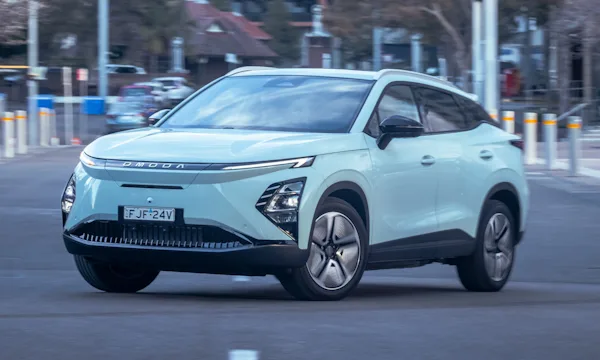 Omoda 5 elétrico verde de frente fazendo uma curva no meio da rua de uma cidade 