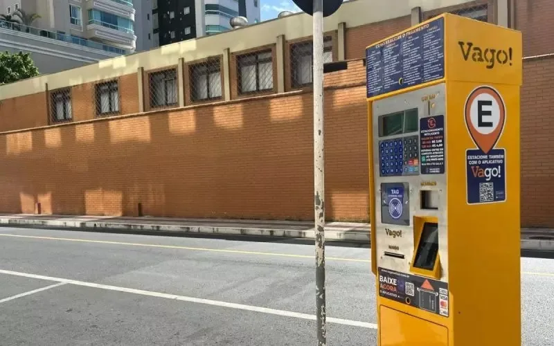 Torre de estacionamento rotativo amarela com prédio de tijolos ao fundo