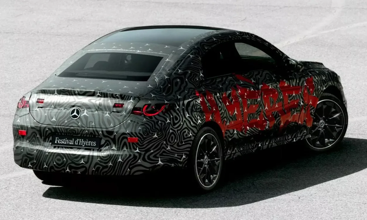 Novo Mercedes-Benz CLA camuflado de cinza, preto e laranja visto de trás com fundo cinza claro