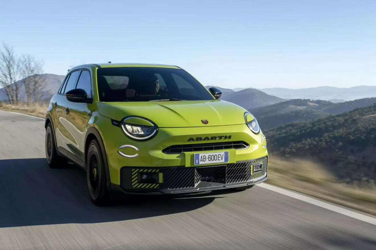 Crossover elétrico Abarth 600e amarelo em foto de dianteira na estrada com montanhas ao fundo