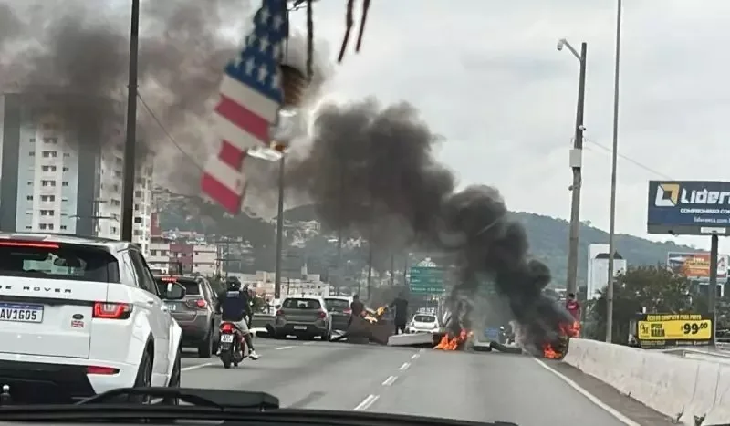 Incêndio provocado por pessoas em via importante no Sul do Brasil com carros passando ao lado