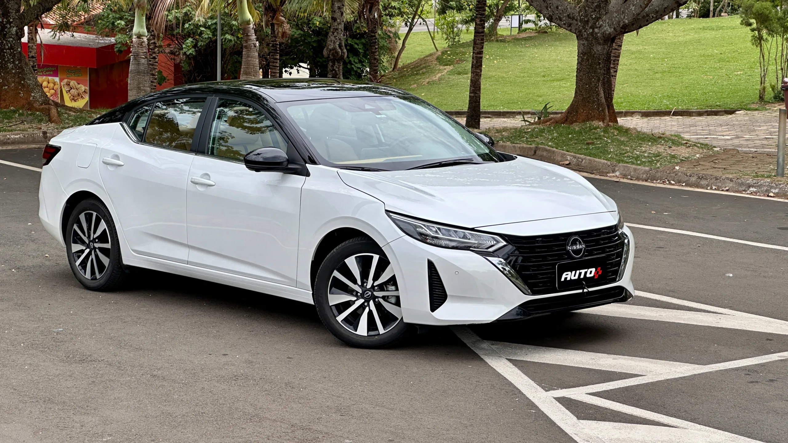 Nissan sentra exclusive branco com teto preto parado em frente árvores bem grandes