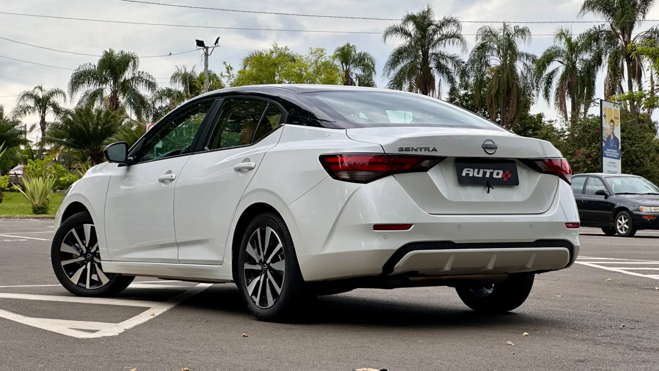 Nissan sentra exclusive branco com teto preto parado em frente árvores bem grandes