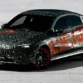 Novo Mercedes-Benz CLA camuflado de cinza, preto e laranja visto de frente com fundo cinza claro