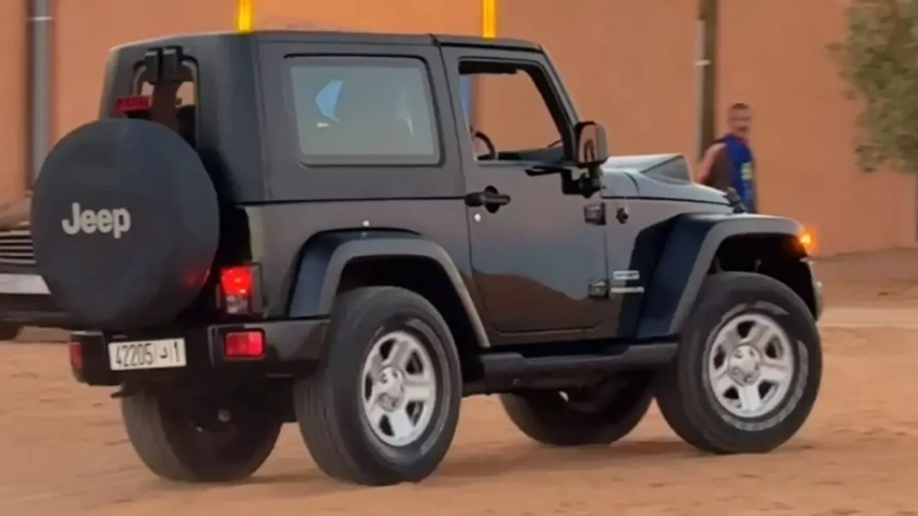 Jeep Wrangler preto encurtado em foto de traseira  no Marrocos na areia