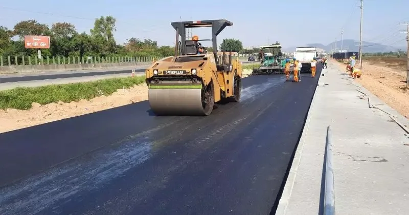 obras na BR-101 com máquina deixando asfalto mais liso e trabalhadores ao fundo