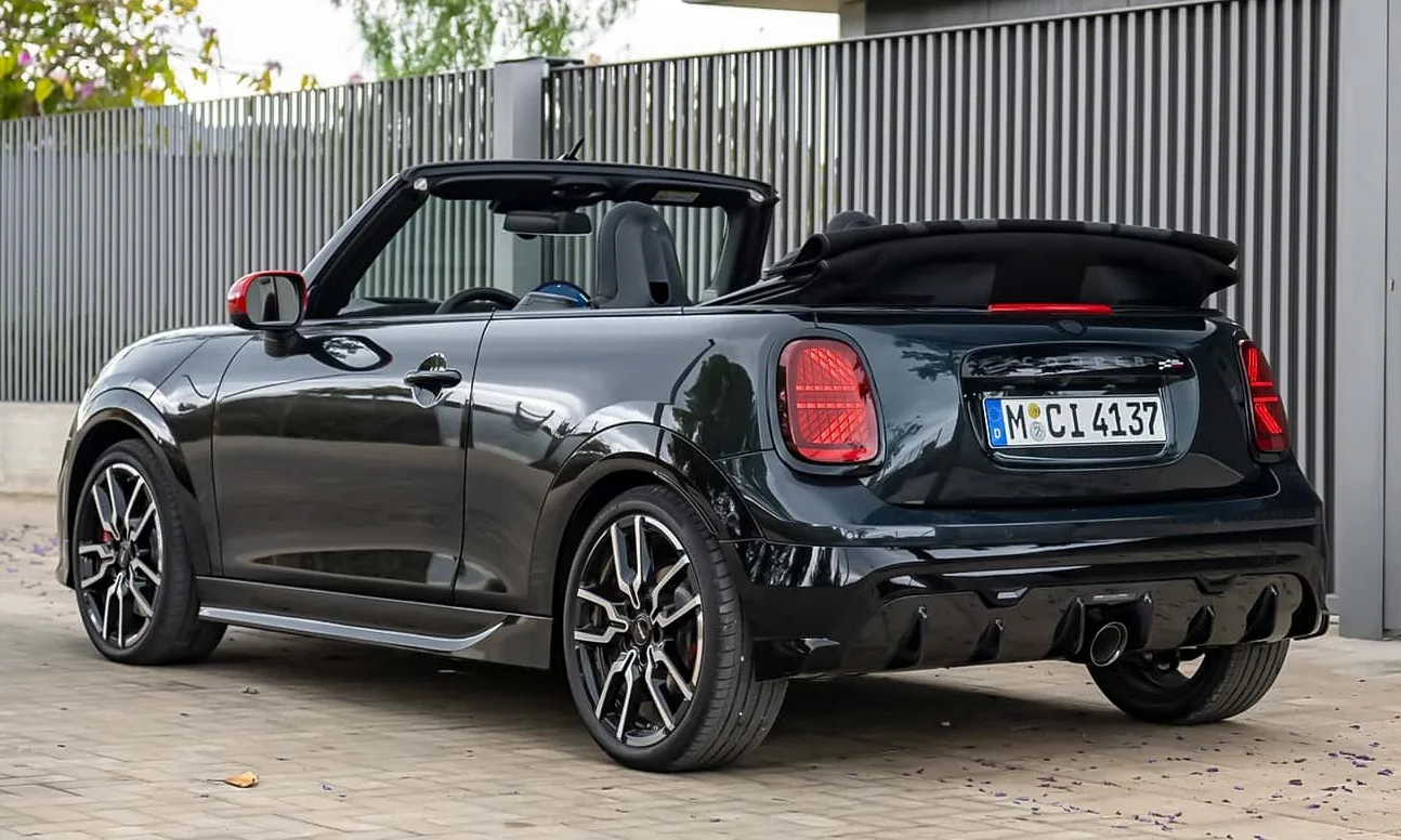 Novo Mini JCW conversível preto com teto aberto parado ao lado de um prédio