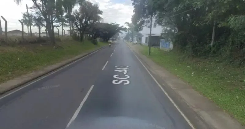 Imagem de uma rua localizada em Santa Catarina com uma moto de farol aceso