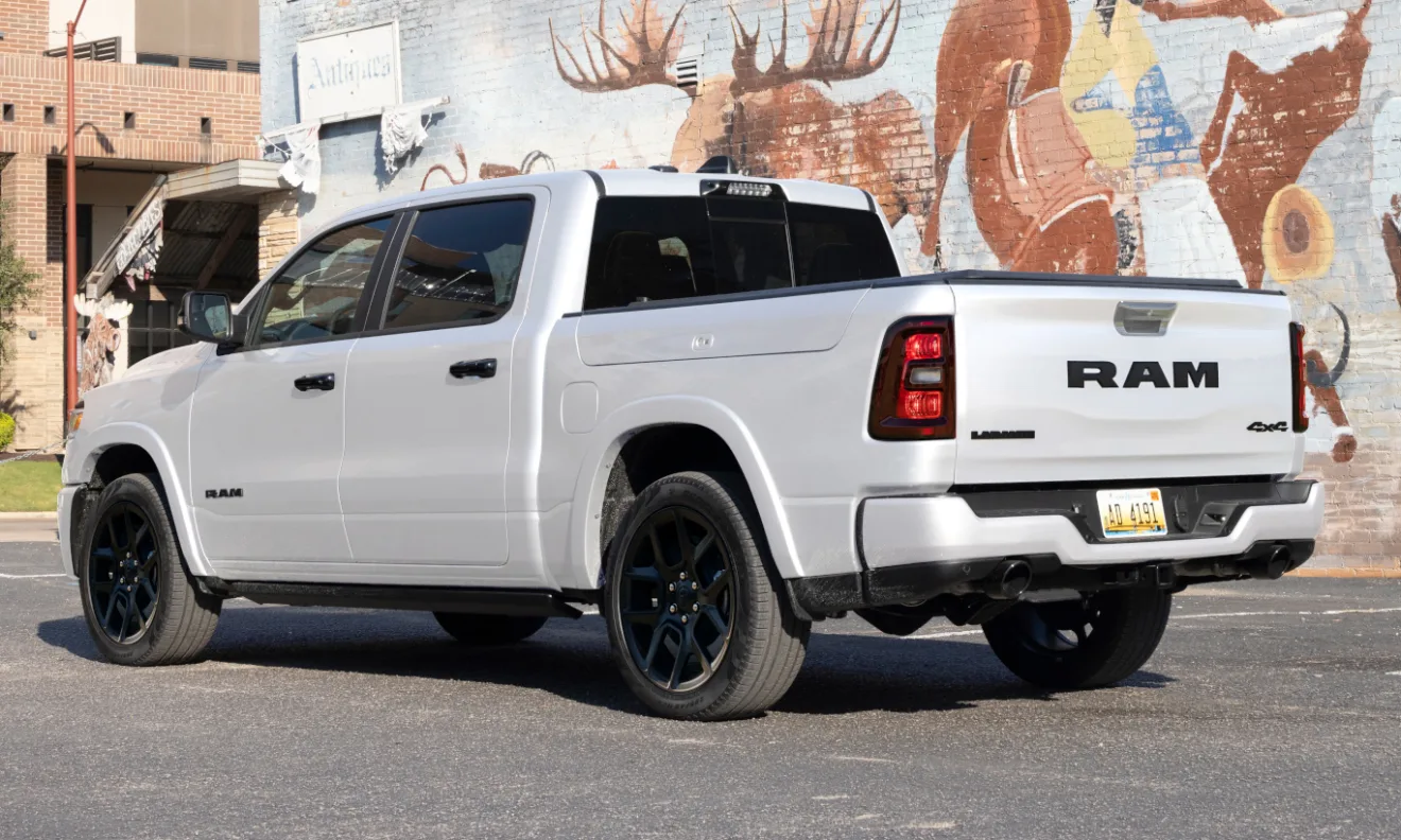 Ram 1500 branca de traseira estacionada com rodas pretas e ao fundo um muro grafitado