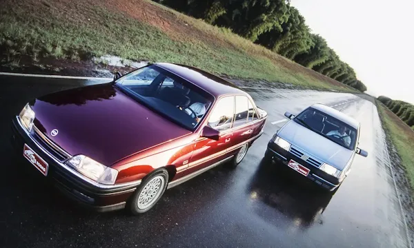 Chevrolet omega bordô em uma reta molhada sendo perseguido por um Fiat Tempra prata