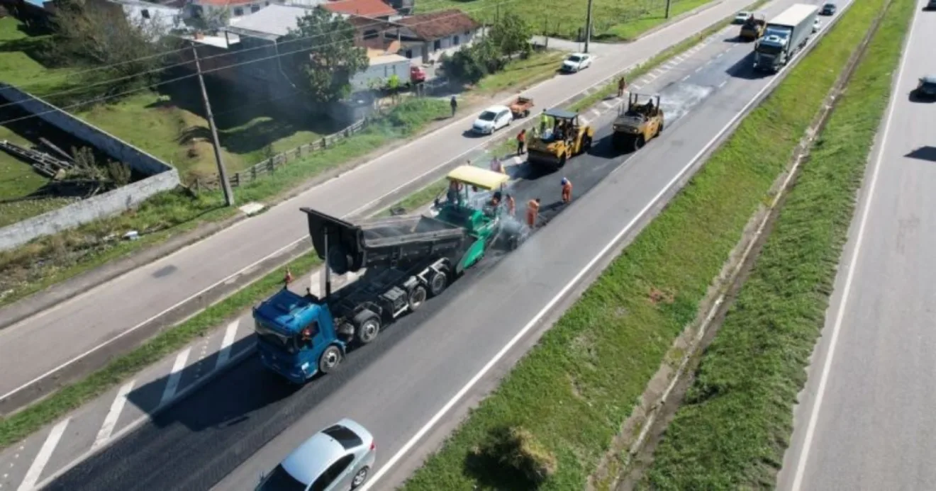 Obras na BR-101 em Santa Catarina com maquinário funcionado e caminhão azul descarregando carga