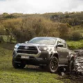 Toyota Hilux 2025 no fora de estrada na lama com vegetação e árvores ao fundo