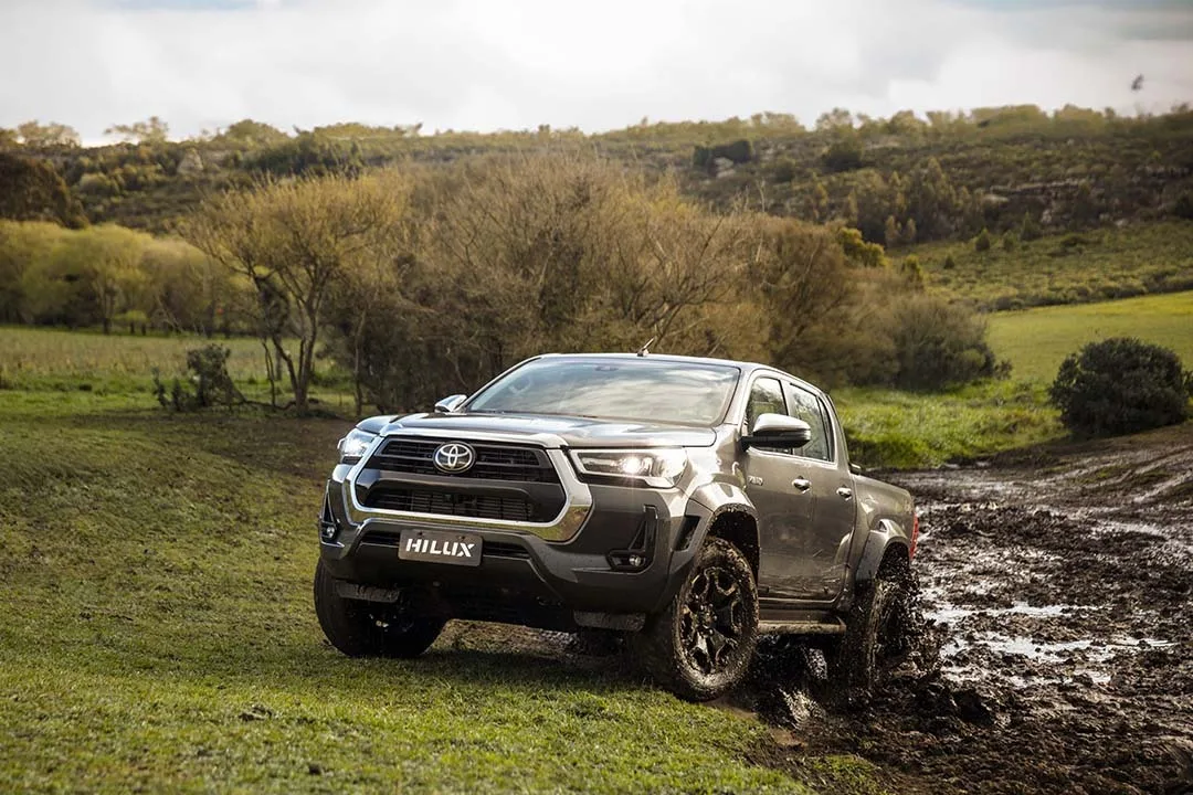 Toyota Hilux 2025 no fora de estrada na lama com vegetação e árvores ao fundo