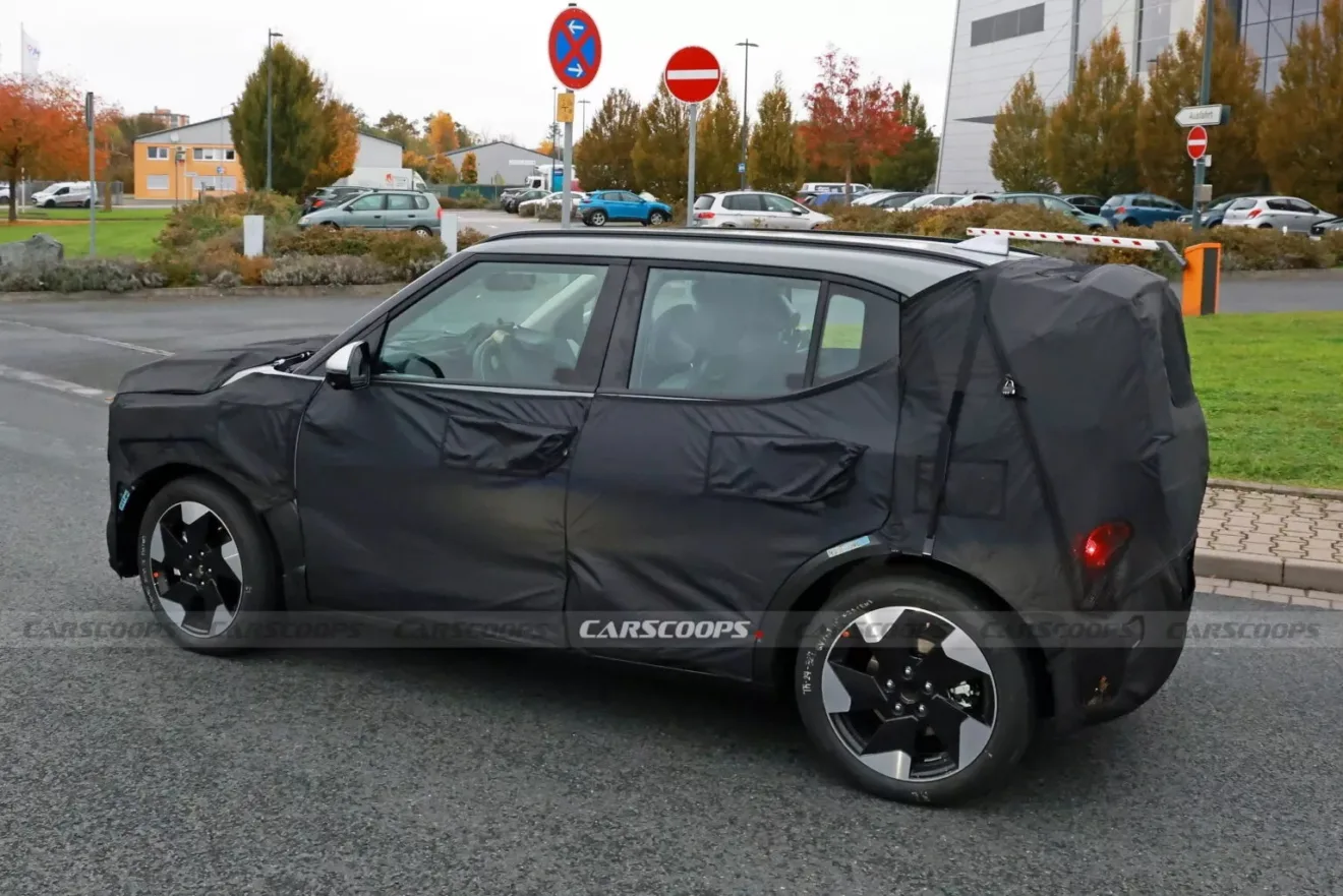 Novo SUV elétrico EV2 da Kia fazendo teste na rua, camuflado de preto e visto lateralmente